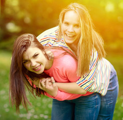 Two young girl friends in a hug at park
