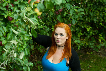 Red hair girl in pin-up style picking an apple