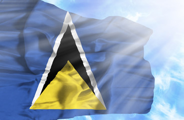 St Lucia waving flag against blue sky with sunrays