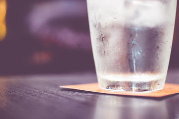 Vintage filter : Cold glass of water on wooden table at restaura