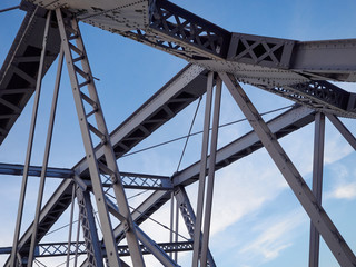 Detail of painted riveted bridge against blue sky.