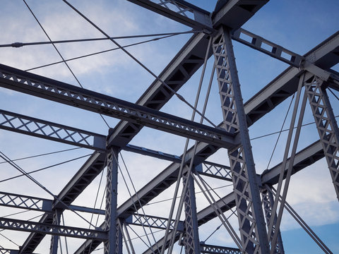 Detail of painted riveted bridge against blue sky. - Powered by Adobe