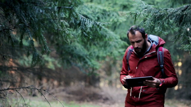 Young, lost man with tablet looking for direction on the forest
