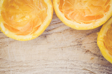 half cut squeezed oranges on a wood background