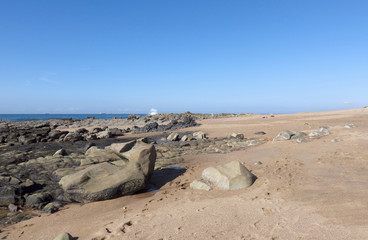 Rocks Exposed at Low Tide on Empty Beach