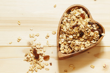 Homemade muesli in a bowl in the shape of a heart on a wooden ta