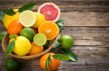 Fresh and juicy citrus fruits in the basket on the rustic table - obrazy, fototapety, plakaty