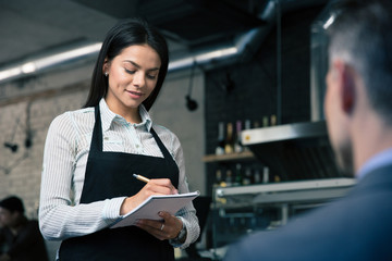 Fototapeta na wymiar Female waiter in apron writing order