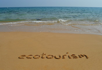Text  'ecotourism' in the sand