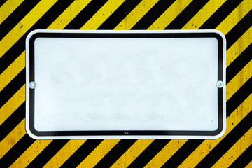 White sign on a concrete wall with black and yellow stripes