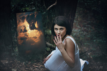 Magical mirror and surprised woman in dark forest