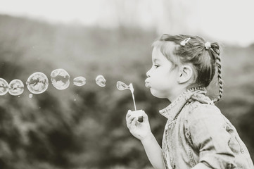 Happy little pretty girl outdoor in the park blowing bubbles © bedya