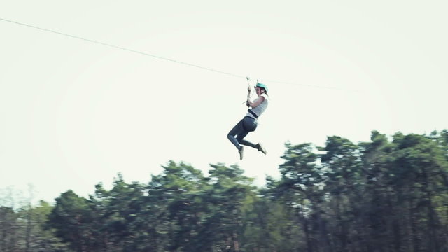 Woman sliding on a zip line in an adventure park, slow motion