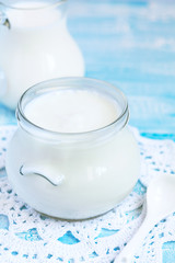 Homemade yogurt in a glass jar on a blue table, selective focus
