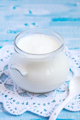 Homemade yogurt in a glass jar on a blue table, selective focus
