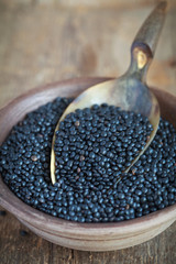 Dry black lentil beluga in a clay bowl and in a scoop