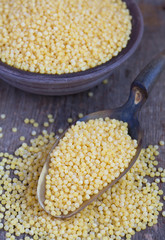 Dry Israeli couscous ptitim in a clay bowl and in the scoop on w