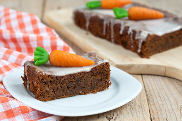 A piece of carrot cake with nuts, decorated with marzipan carrot