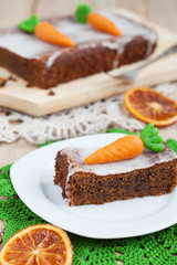 A piece of carrot cake with nuts, decorated with marzipan carrot