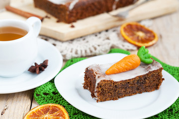 A piece of carrot cake with nuts, decorated with marzipan carrot