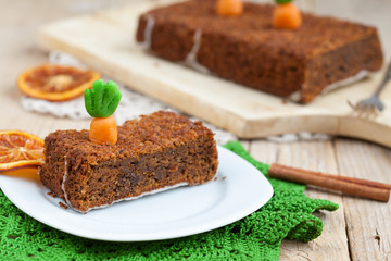 A piece of carrot cake with nuts, decorated with marzipan carrot