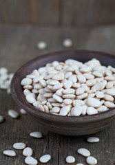 Fototapeta na wymiar Dry white baby lima beans in a clay bowl on wooden table