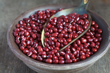Dry red adzuki beans in a clay bowl on wooden table