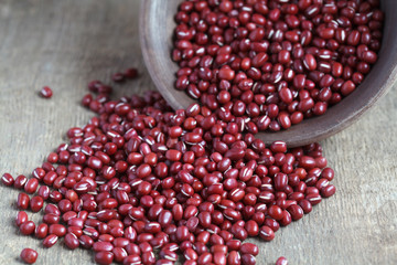 Dry red adzuki beans in a clay bowl on wooden table