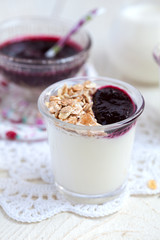 Small jar with homemade yogurt with blackcurrant jam and granola