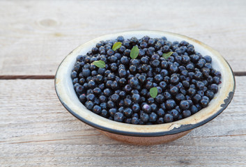 Ripe wild blueberries in a old bowl on the table, closeup