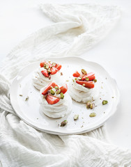 Obraz na płótnie Canvas Small strawberry and pistachio pavlova meringue cakes with