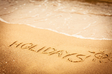 The word holidays written in the sand on a beach