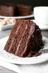 Delicious chocolate cake in white plate on wooden table background, closeup