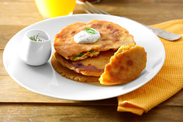 Stack of corn tortillas with stuffing and glass of juice on wooden table background