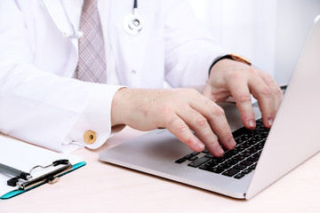 Doctors hands working at notebook in office on white background