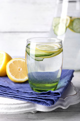 Fresh water with lemon and cucumber in glassware on wooden background