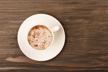 Cup of coffee on wooden table, top view