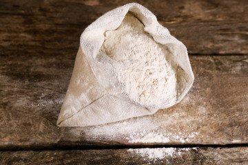 Bag of white flour on wooden background