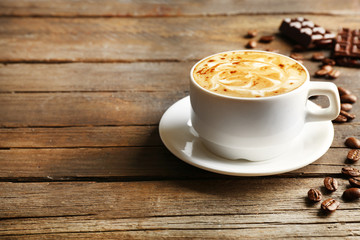 Cup of coffee latte art with grains and chocolate on wooden background