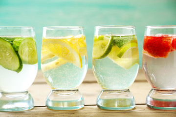 Glasses of different home made freshness healthy vitamin-fortified water on wooden table