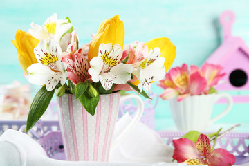 Fototapeta na wymiar Beautiful flowers in cup, on color wooden background