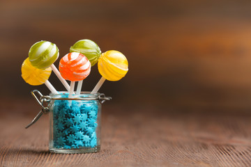 Colorful candies in jar on table on wooden background