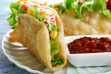 Tasty taco with tomato dip on plate on table close up