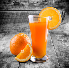 Orange juice glass and fresh oranges on wood