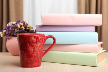 Books, cup and plant on wooden table, closeup