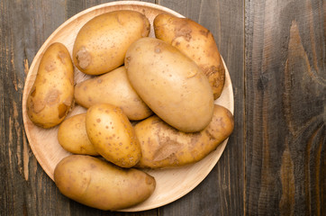 Raw potatoes on wooden plate