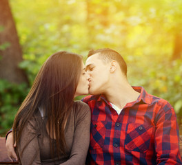 Couple kissing at the bench in park