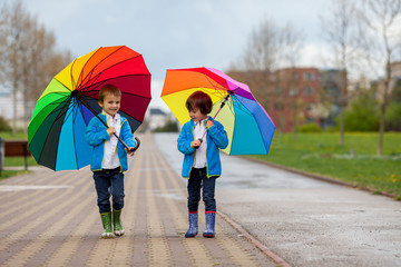 Two adorable little boys, walking in a park on a rainy day, play