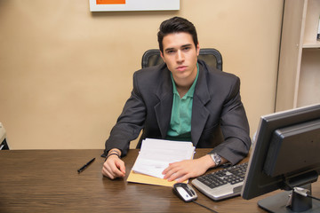 Handsome young businessman sitting at desk in office