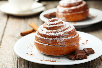 Cinnamon buns on plate on grey wooden background